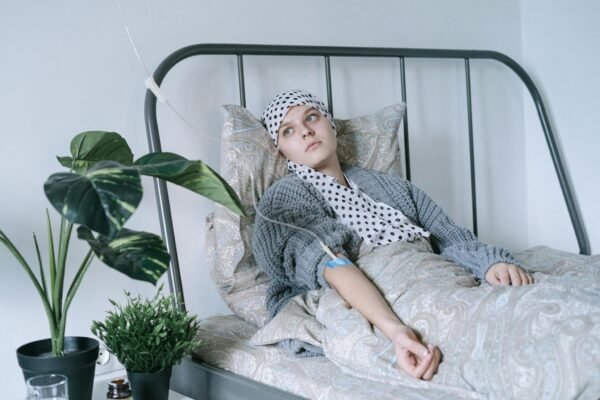 Woman in Gray and White Hijab Sitting on White Bed